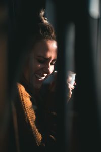 smiling woman holding white ceramic mug